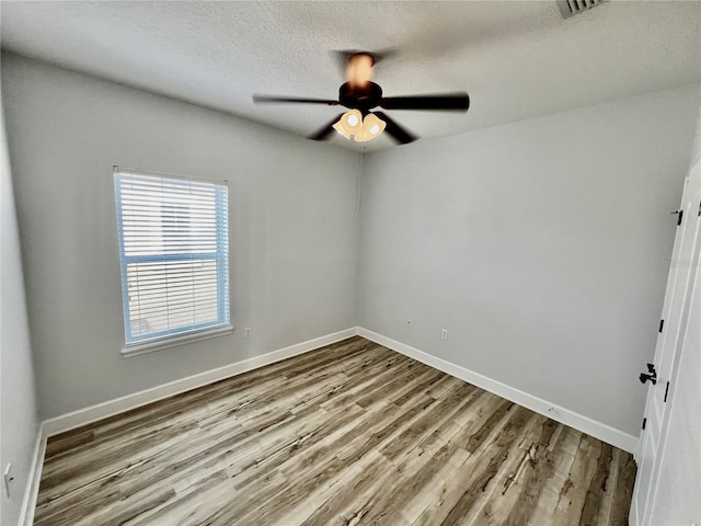 spare room with ceiling fan, light wood-type flooring, and a textured ceiling