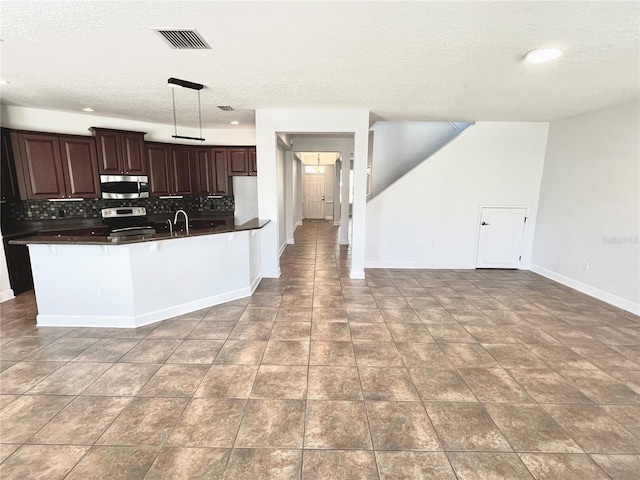 kitchen with sink, hanging light fixtures, stainless steel appliances, decorative backsplash, and dark brown cabinets