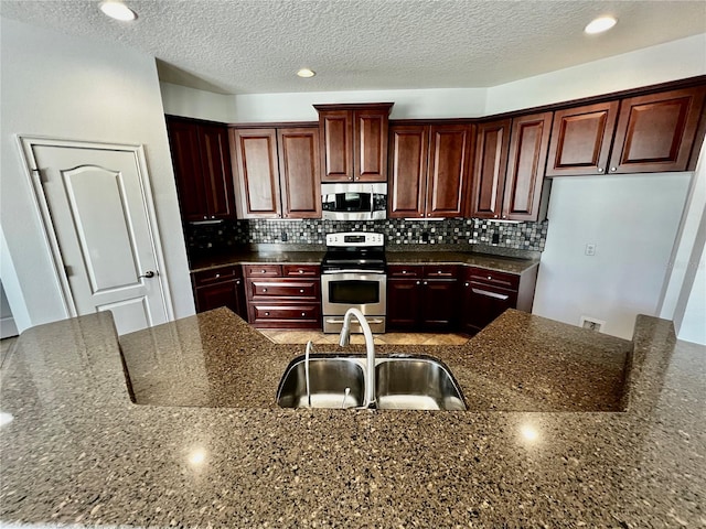 kitchen featuring dark stone counters, backsplash, stainless steel appliances, and a textured ceiling