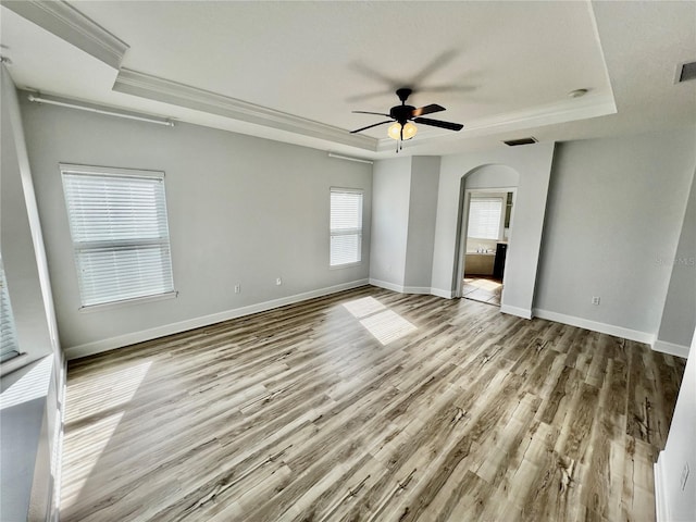 empty room featuring a raised ceiling, ceiling fan, and light hardwood / wood-style floors