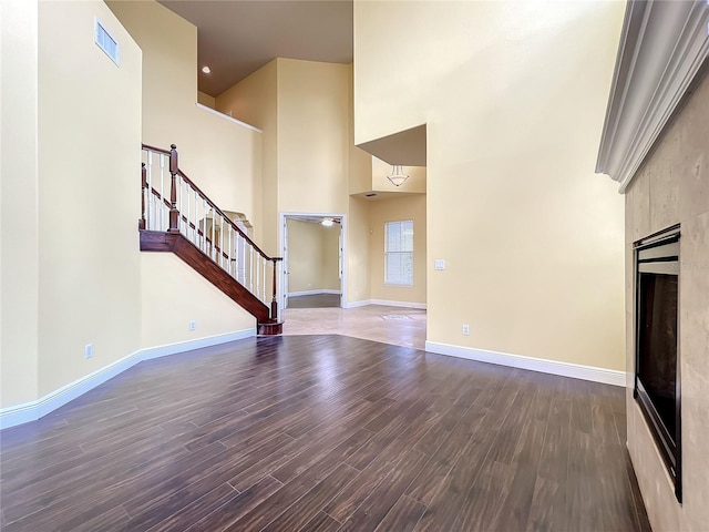 unfurnished living room with dark wood-type flooring and a high ceiling