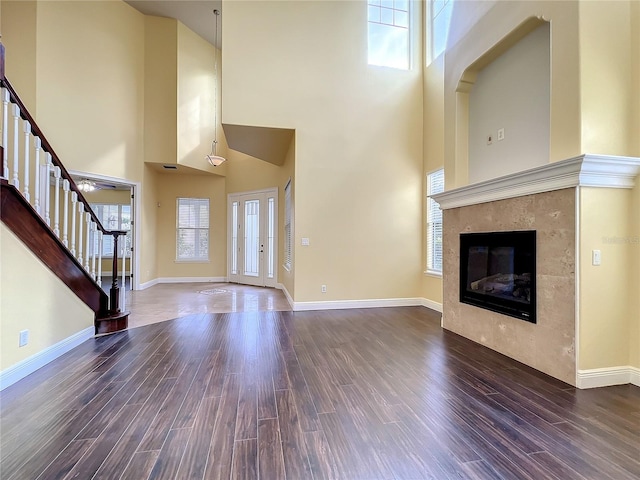 unfurnished living room featuring a healthy amount of sunlight, dark hardwood / wood-style flooring, and a high ceiling