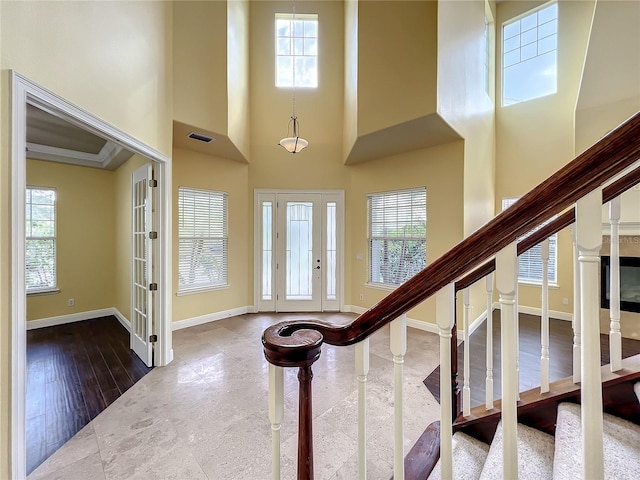 entrance foyer with wood-type flooring, a towering ceiling, plenty of natural light, and ornamental molding