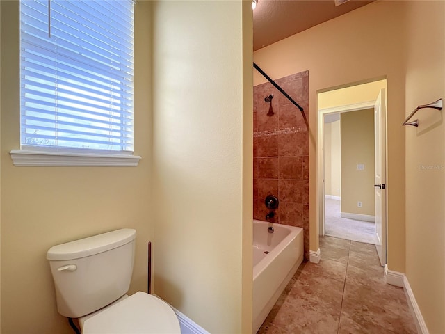 bathroom featuring tile patterned flooring, toilet, and tiled shower / bath