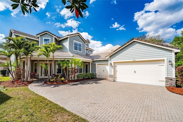 view of front of home with stone siding, french doors, decorative driveway, and a garage