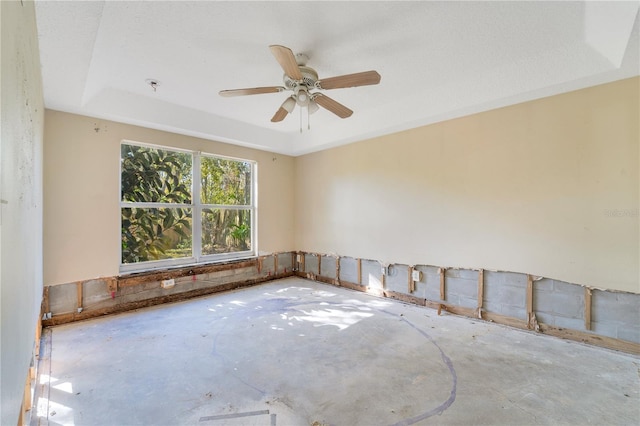 unfurnished room featuring ceiling fan, concrete floors, and a tray ceiling