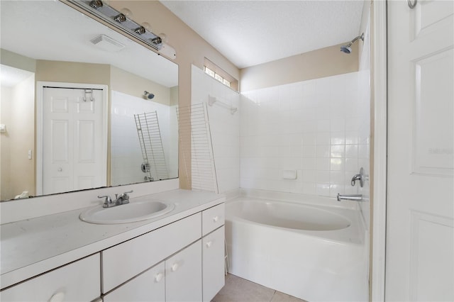 bathroom featuring vanity, tile patterned floors, a textured ceiling, and tiled shower / bath combo