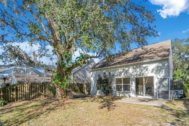 rear view of property with cooling unit, a yard, and a patio