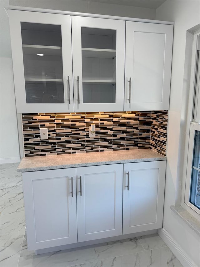 details featuring backsplash, white cabinetry, and light stone countertops