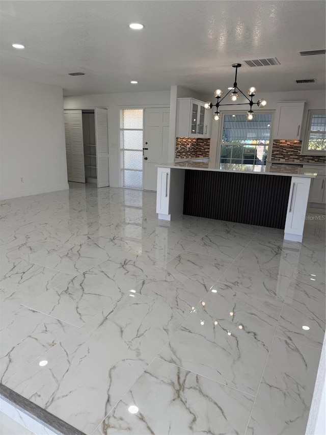 kitchen featuring decorative light fixtures, tasteful backsplash, white cabinetry, and a notable chandelier