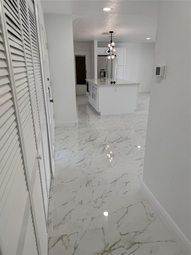 hallway featuring a textured ceiling and an inviting chandelier