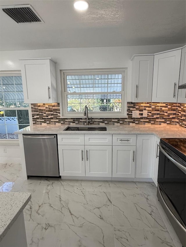 kitchen featuring backsplash, white cabinetry, sink, and appliances with stainless steel finishes