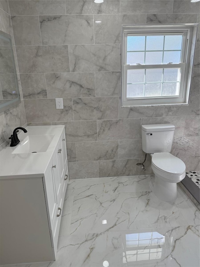 bathroom featuring vanity, toilet, and tile walls