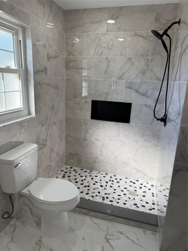 bathroom featuring toilet and a tile shower