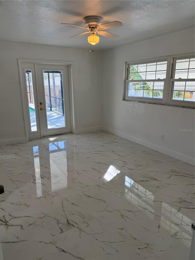 empty room with ceiling fan and a textured ceiling