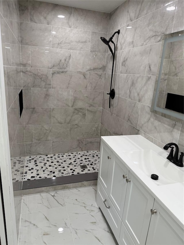 bathroom with tiled shower and vanity