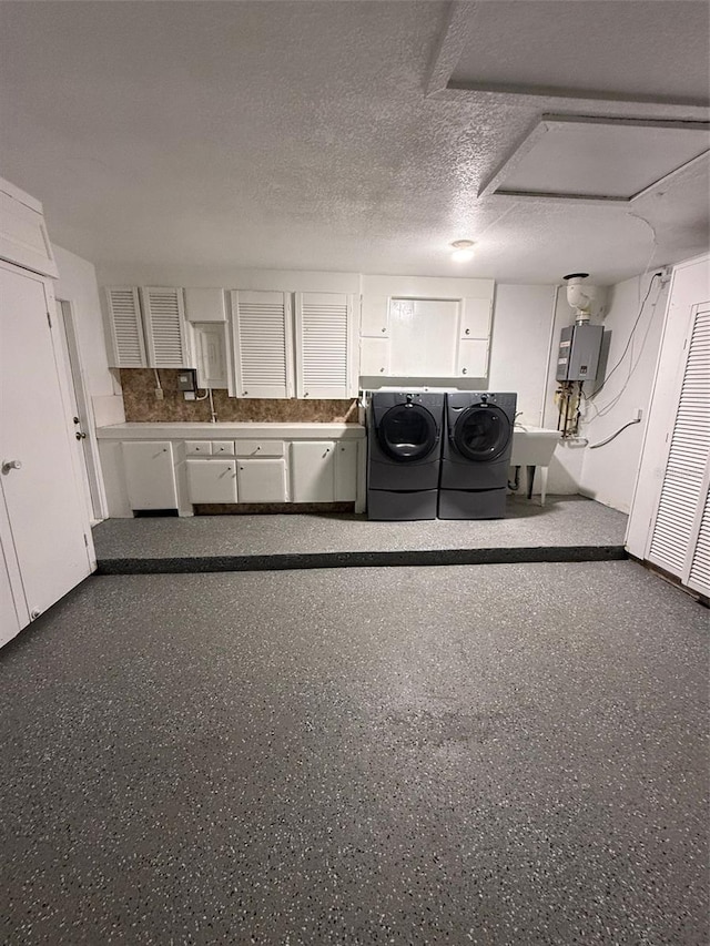 laundry area featuring cabinets, sink, washer and dryer, a textured ceiling, and water heater