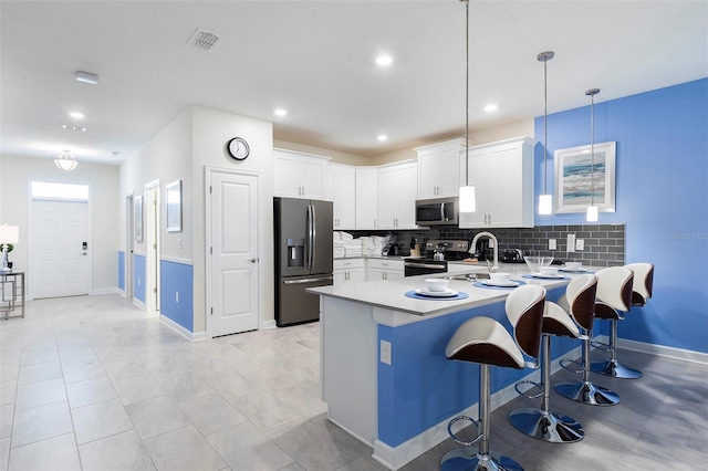 kitchen with stainless steel appliances, white cabinetry, and hanging light fixtures