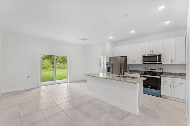 kitchen with a kitchen island with sink, white cabinets, sink, light stone counters, and stainless steel appliances