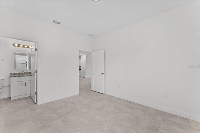 unfurnished bedroom featuring ensuite bathroom and sink