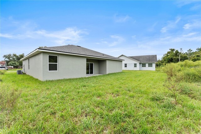 rear view of property with a lawn and central air condition unit