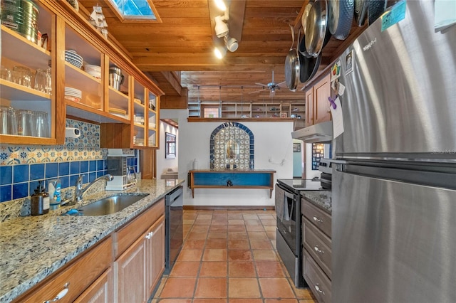 kitchen featuring light stone countertops, sink, rail lighting, stainless steel appliances, and backsplash