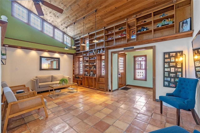 living area with a towering ceiling, ceiling fan, and wooden ceiling