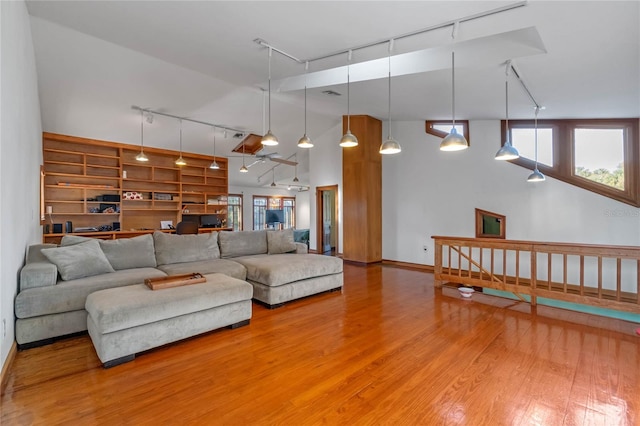 living room featuring hardwood / wood-style floors, track lighting, and high vaulted ceiling