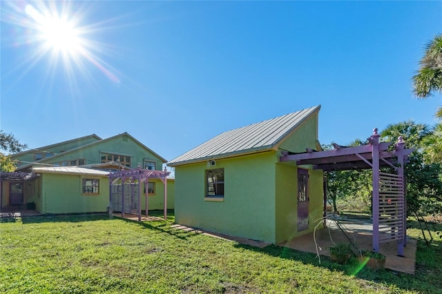 rear view of house featuring a pergola and a yard