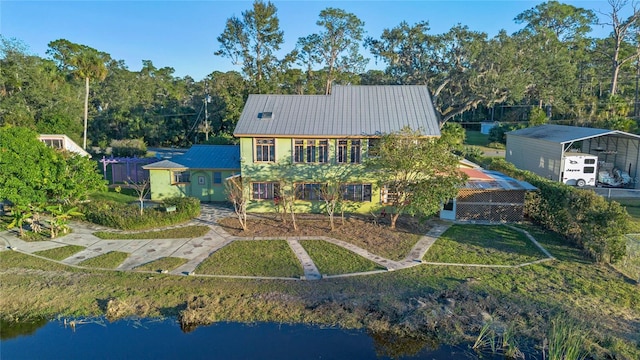 rear view of property with a water view, a carport, and a lawn