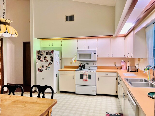 kitchen featuring white appliances, light floors, visible vents, a sink, and light countertops