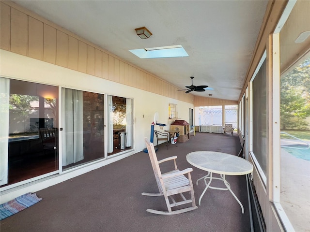 sunroom / solarium featuring lofted ceiling with skylight and ceiling fan