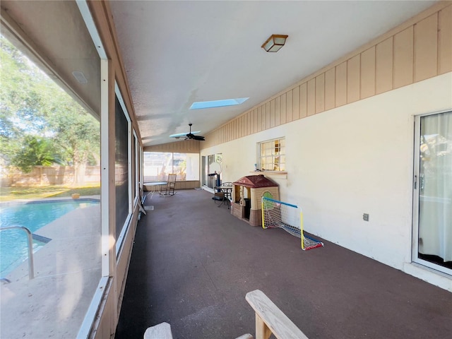 unfurnished sunroom with vaulted ceiling with skylight and a ceiling fan