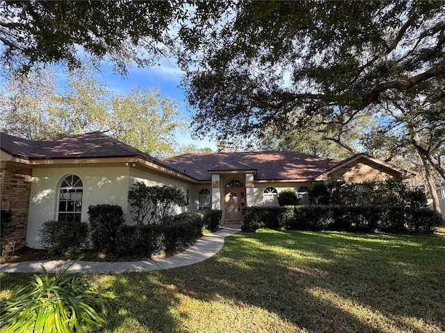 single story home with stucco siding, brick siding, and a front yard