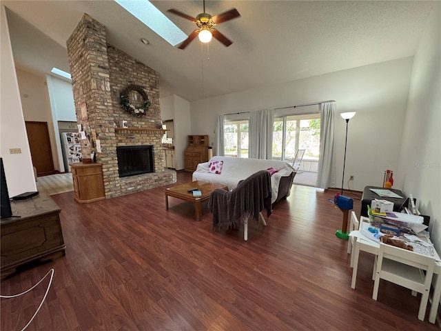 living area featuring a fireplace, a skylight, wood finished floors, high vaulted ceiling, and a ceiling fan