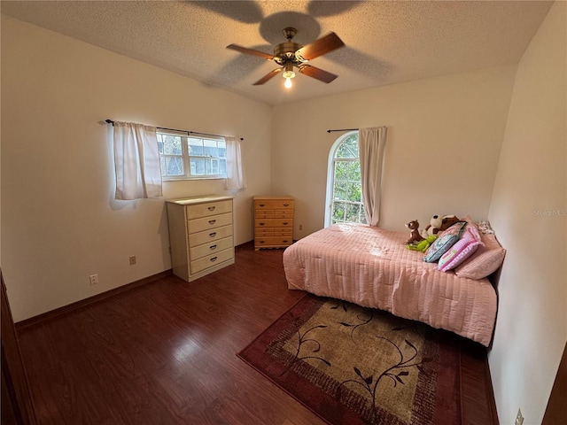 bedroom with a ceiling fan, dark wood-style floors, baseboards, and a textured ceiling