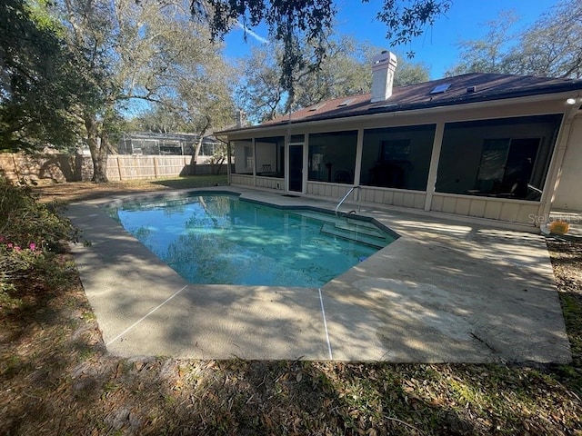 view of swimming pool featuring a patio area, fence, a fenced in pool, and a sunroom