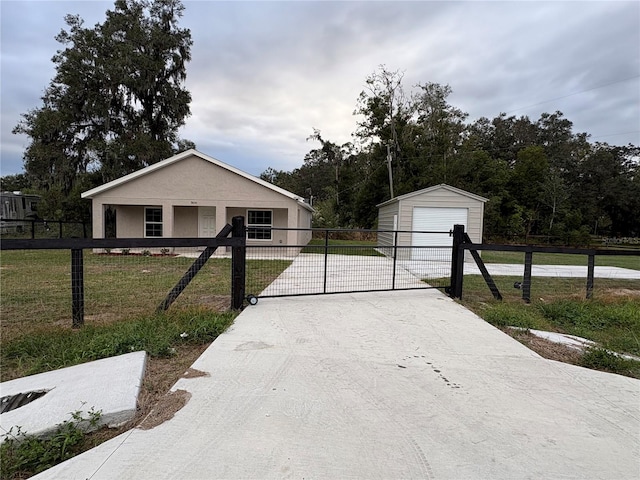 view of front of house with an outbuilding, a fenced front yard, a garage, stucco siding, and a front lawn