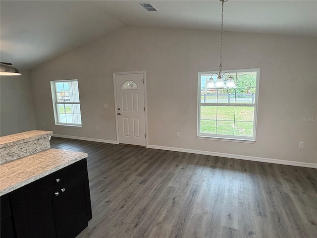 unfurnished dining area with lofted ceiling, a notable chandelier, dark wood-type flooring, visible vents, and baseboards