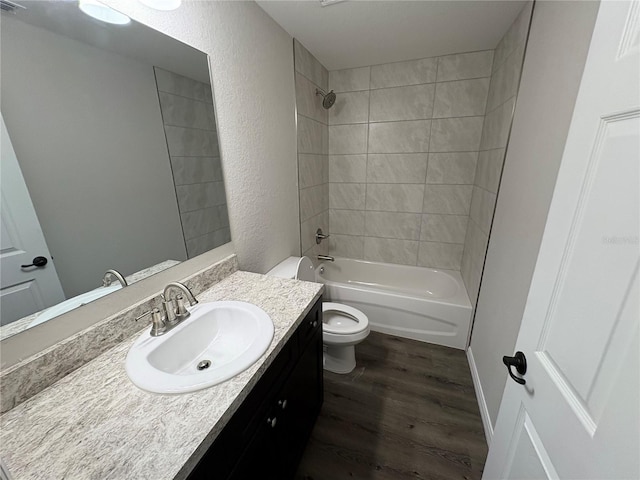 bathroom with shower / washtub combination, a textured wall, toilet, vanity, and wood finished floors