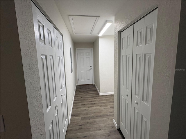 hall featuring baseboards, dark wood finished floors, and a textured wall