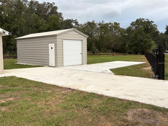 detached garage with concrete driveway and fence