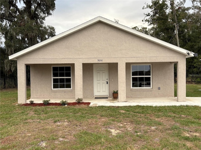 view of front of property featuring covered porch, a front lawn, and stucco siding