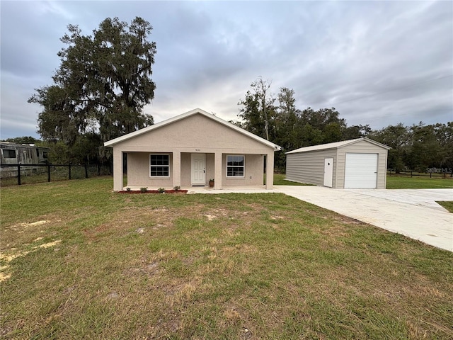 view of front of home featuring a detached garage, fence, an outdoor structure, a front lawn, and stucco siding