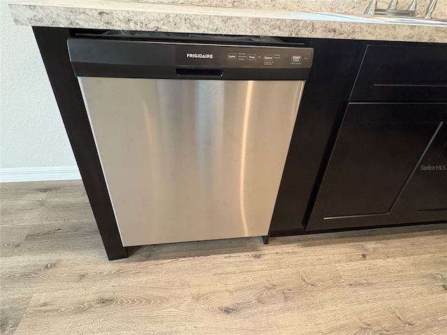 interior details with stainless steel dishwasher, light wood-type flooring, dark cabinetry, and baseboards