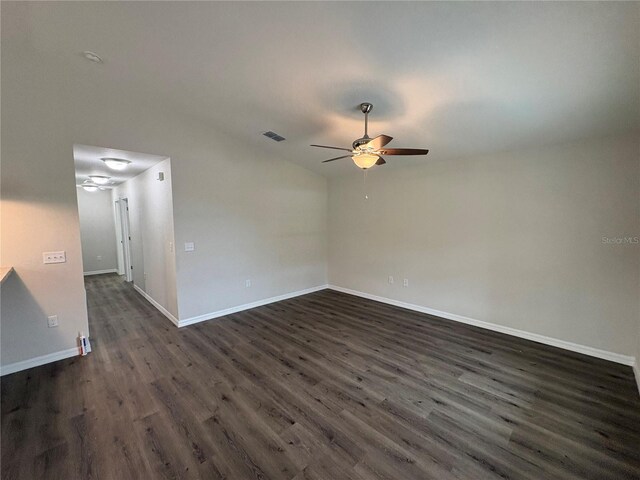 unfurnished room featuring dark wood-style floors, visible vents, ceiling fan, and baseboards