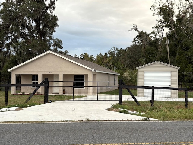 view of front of house featuring a fenced front yard, concrete driveway, a detached garage, and stucco siding