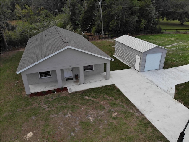 view of front of property featuring an outbuilding, a detached garage, a front yard, a patio area, and fence