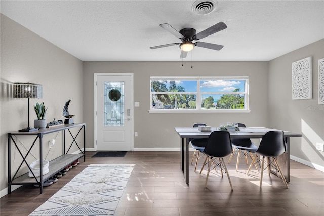 dining area with a textured ceiling, ceiling fan, and dark wood-type flooring