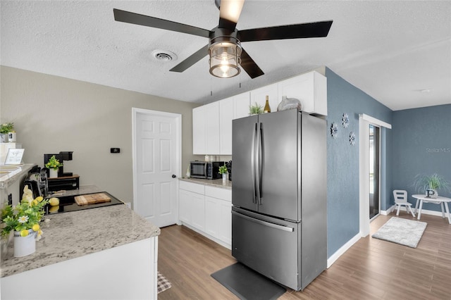 kitchen featuring a textured ceiling, light wood-type flooring, stainless steel appliances, and white cabinetry